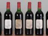 six bottles of wine are lined up on a wooden table