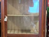 a display cabinet with a glass door in the middle of a room