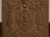 une plaque en pierre sur laquelle figurent des armoiries et une couronne