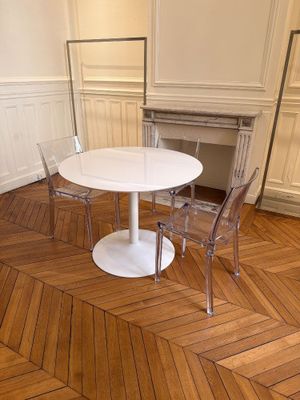 une table et des chaises blanches dans une pièce au sol en parquet