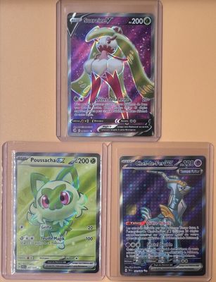 Trois cartes Pokémon différentes sont exposées dans une vitrine.