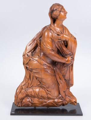 une sculpture en bois représentant une femme assise sur un rocher