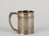 une tasse ancienne en métal argenté avec une anse, sur fond blanc