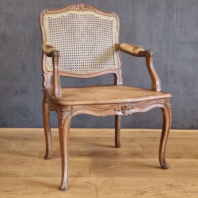 an old wooden chair with wicker seat and armrests on a wooden floor