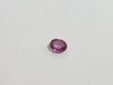 a pink sapphire stone on a white surface