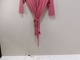 un lit blanc avec une chemise rose accrochée au mur
