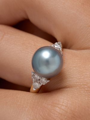 un gros plan de la main d'une personne tenant une bague ornée d'une perle