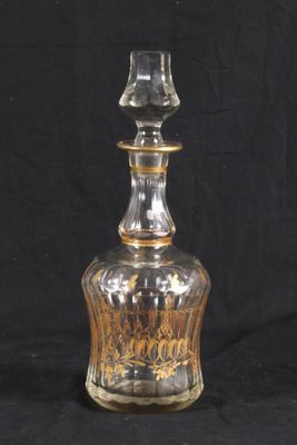 a clear glass bottle with a gold decoration on it