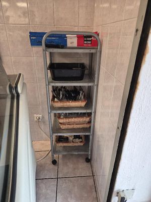 une photo d'une cuisine dans laquelle se trouve une étagère sur laquelle sont posés des ustensiles