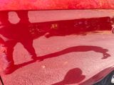 a shadow of a person on the hood of a red car
