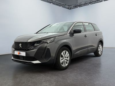 Une voiture grise est garée dans une grande pièce au sol noir.