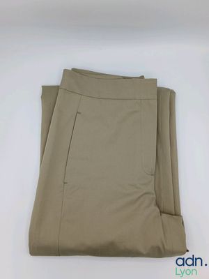 un gros plan sur un pantalon beige posé sur une surface blanche