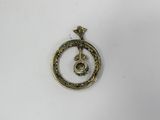 a close up of a gold pendant on a white surface