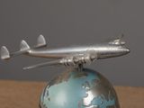 a silver airplane that is sitting on top of a globe