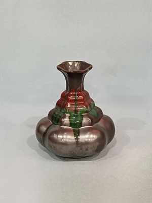 un vase en argent orné d'un motif rouge et vert