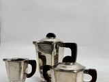 a silver tea pot and two cups sitting on a table