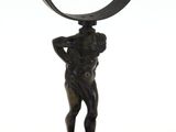 statue en bronze représentant un homme tenant un objet incurvé, posée sur un socle