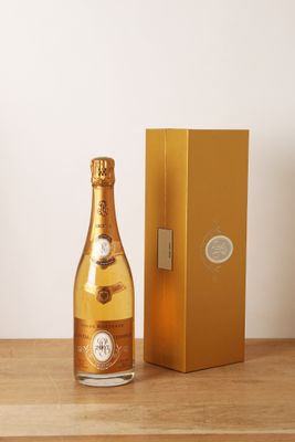 des bouteilles de champagne posées sur une table en bois, à côté d'un coffret doré
