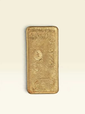 un lingot d'or posé sur une surface blanche, sur fond blanc