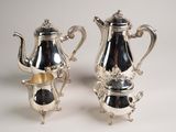 deux théières en argent et une cafetière posées sur une table