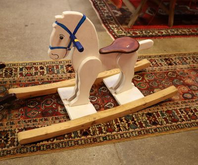 un cheval à bascule en bois posé sur un tapis posé à même le sol