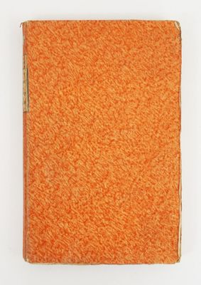 un livre orange à la couverture marron posé sur une surface blanche