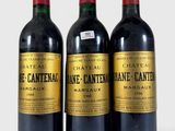 three bottles of red wine sitting next to each other on a white surface