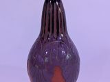 a purple vase that is sitting on a white surface