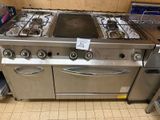 une plaque de cuisson en acier inoxydable à quatre feux et deux fours dans une cuisine