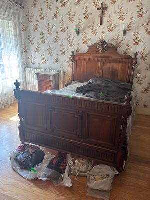 a bed with a wooden headboard and foot board in the middle of a room with floral wallpaper