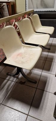 quatre chaises alignées dans une pièce au sol carrelé