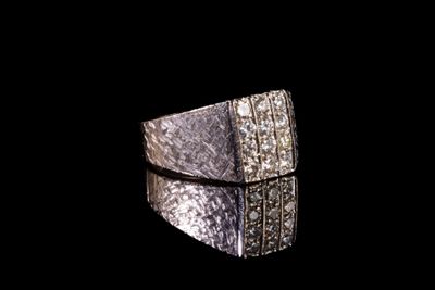 une image représentant une bague en argent sertie de diamants sur fond noir