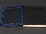 an open book sitting on top of a black table next to a blue book