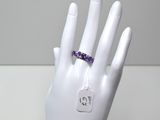 une main sur laquelle est passée une bague sertie de pierres d'améthoralite