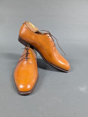 pair of men ' s tan leather shoes with laces on a gray surface