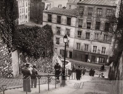 a black and white photo of a group of people walking up a steep hill