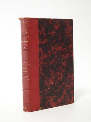 an old book with a red cover sitting on top of a white surface