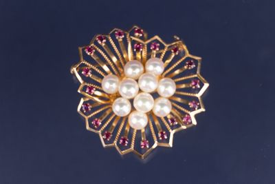une image représentant une broche en or ornée de perles et de grenats