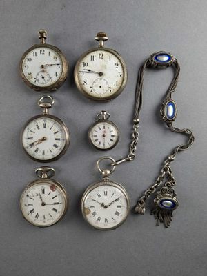 several different types of pocket watches are displayed on a gray surface