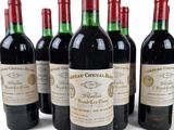 six bottles of red wine lined up in a row on a white surface