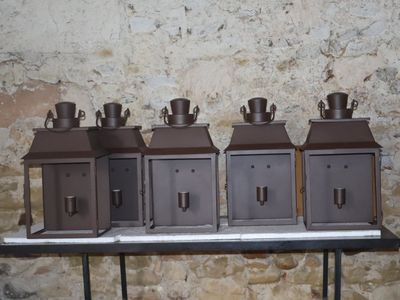 quatre petits récipients en métal posés sur une table, avec un mur en pierre en arrière-plan