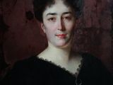 portrait d'une femme en robe noire devant un mur rouge