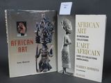 Deux livres sur l'art africain et une œuvre d'art africaine sont posés sur une table