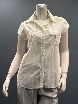 mannequin féminin vêtu d'une chemise et d'un pantalon beiges, sur un présentoir