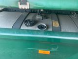 a close up of a green trash can with a yellow tag on it