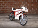 a white and red motorcycle parked in front of a brick wall