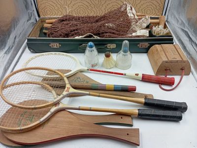 Plusieurs raquettes de tennis sont posées sur une table à côté d'une valise.