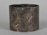 an old silver ring with a design on it on a table