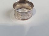 a silver ring on a white surface with a coin in the middle