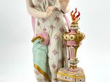 a figurine of a woman standing next to a vase